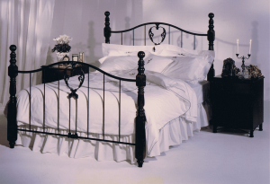 a bed with white sheets and a black metal frame queen