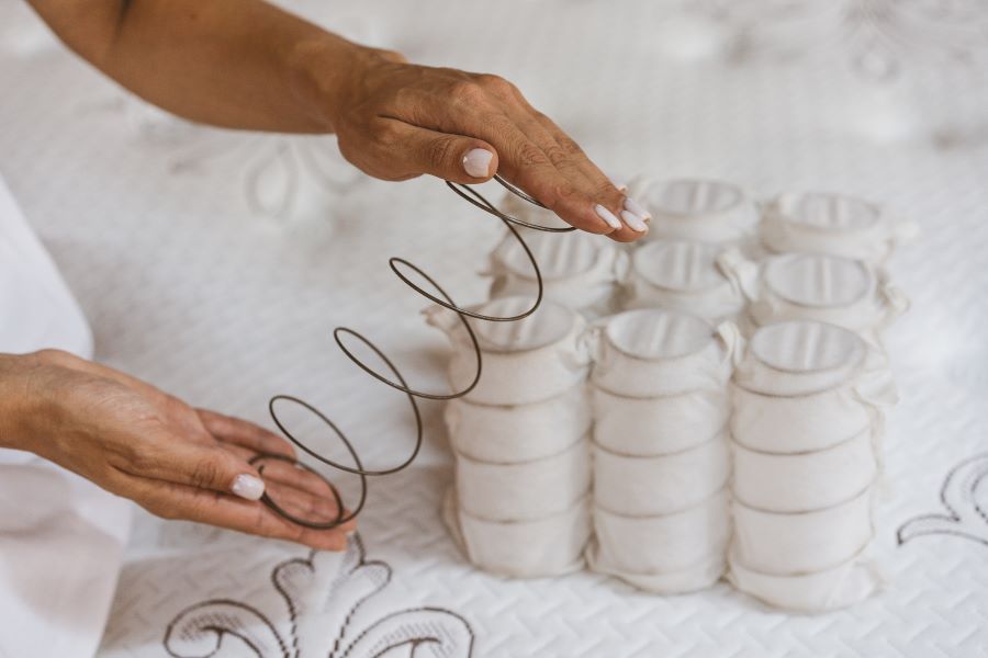 A person is holding the springs of a mattress.