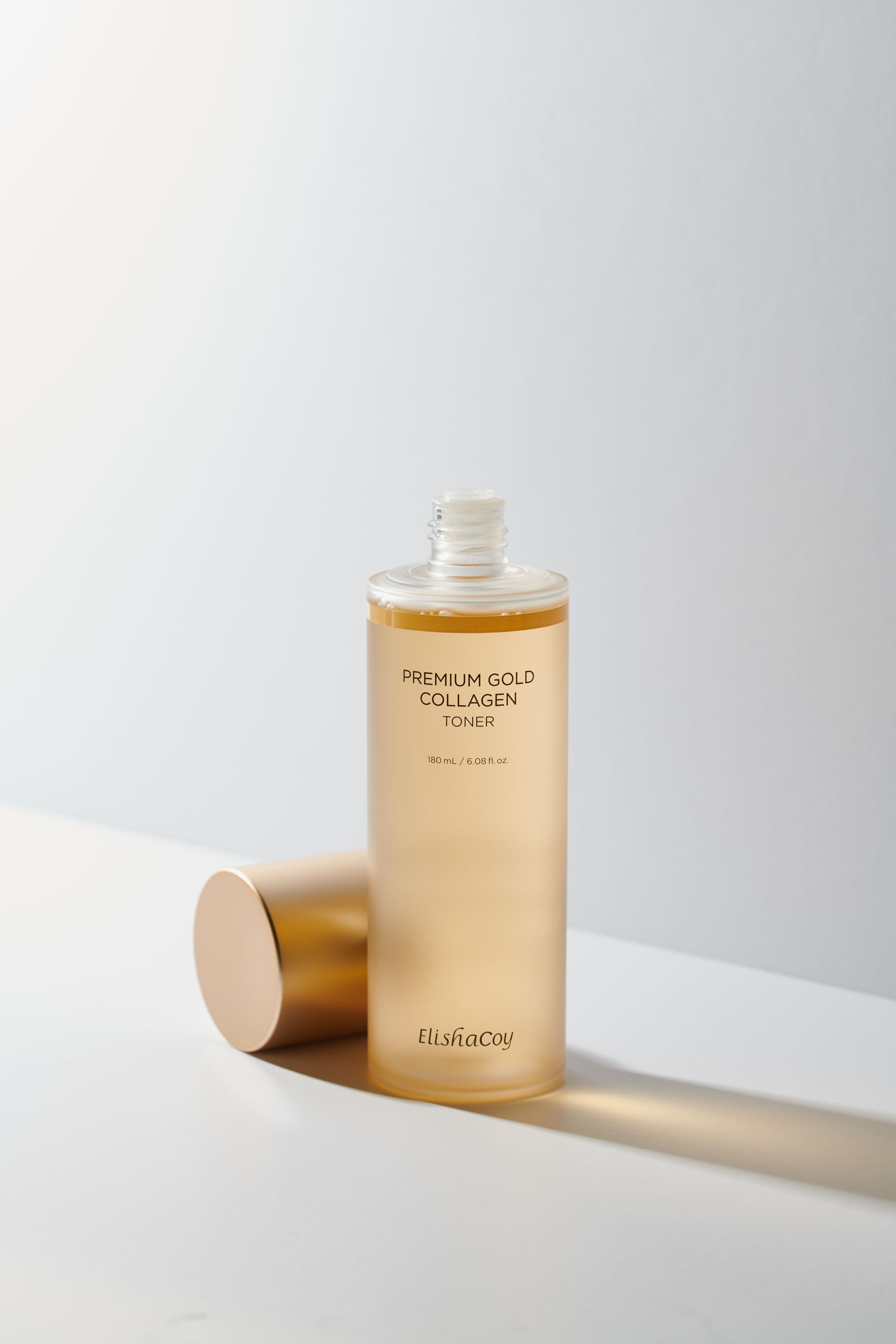 Elisha Coy 爽膚水廣告，金色瓶身，附文字說明。宣傳其含有金色顆粒，並具有膠原蛋白功效。