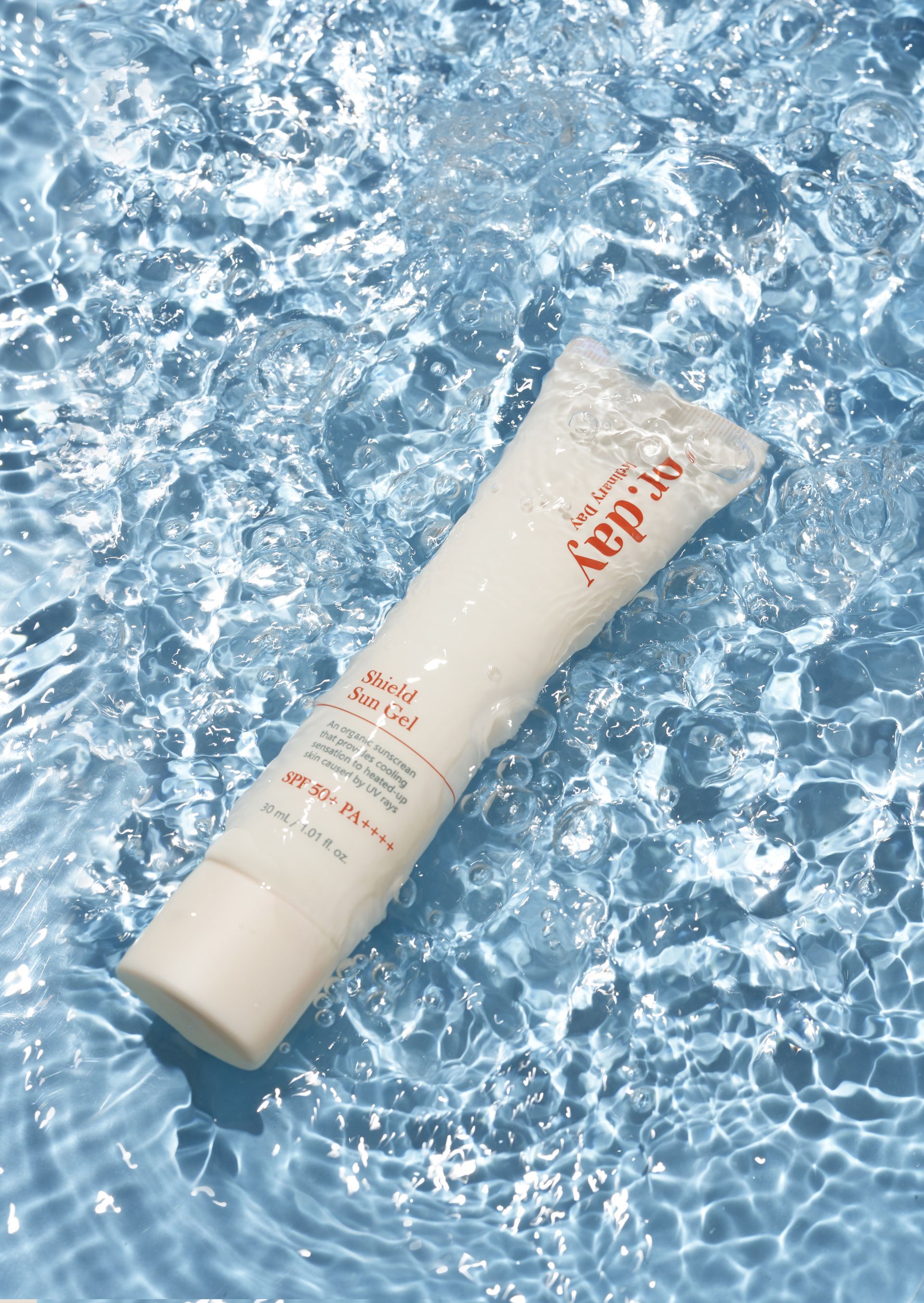 印有中英文字樣的防曬乳管。背景是藍色的海水和樹葉。