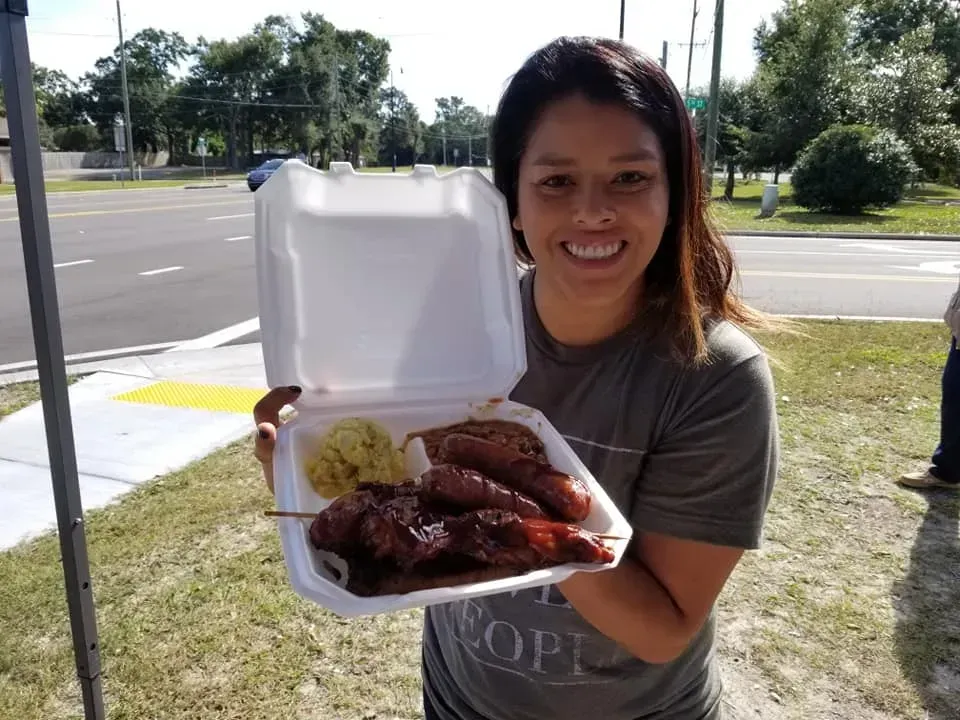 J-Boogie’s Tasty Creations customers showing appreciation and holding BBQ products during a special event.
