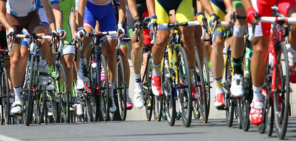 Ciclisti con maglie colorate in bicicletta su una strada asfaltata.