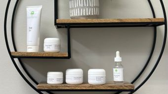 Various skincare products assembled on a three-tiered wooden shelf