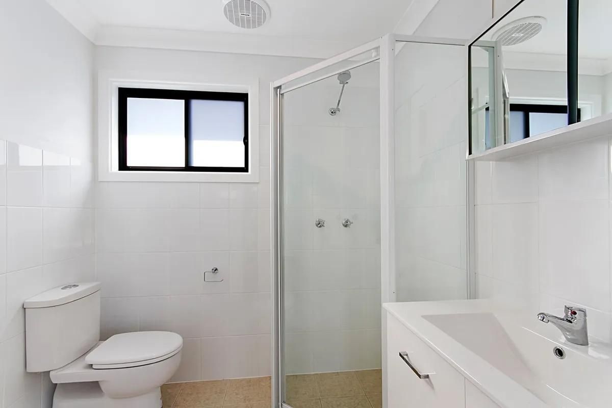 A Bathroom with A Toilet, Sink, Shower and Window — All Trade Renovations- Peter Whelan in Tumbi Umbi, NSW