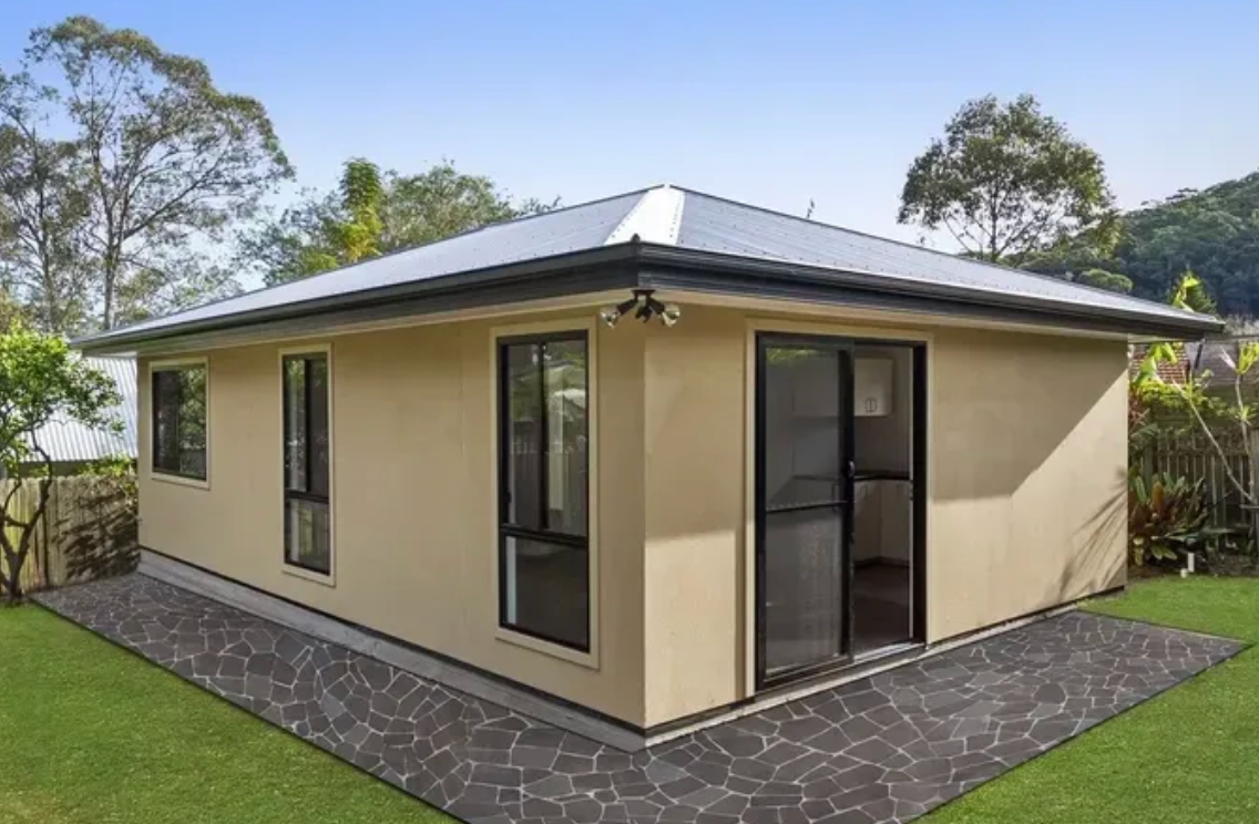 The back of a home enclosed by a green backyard.