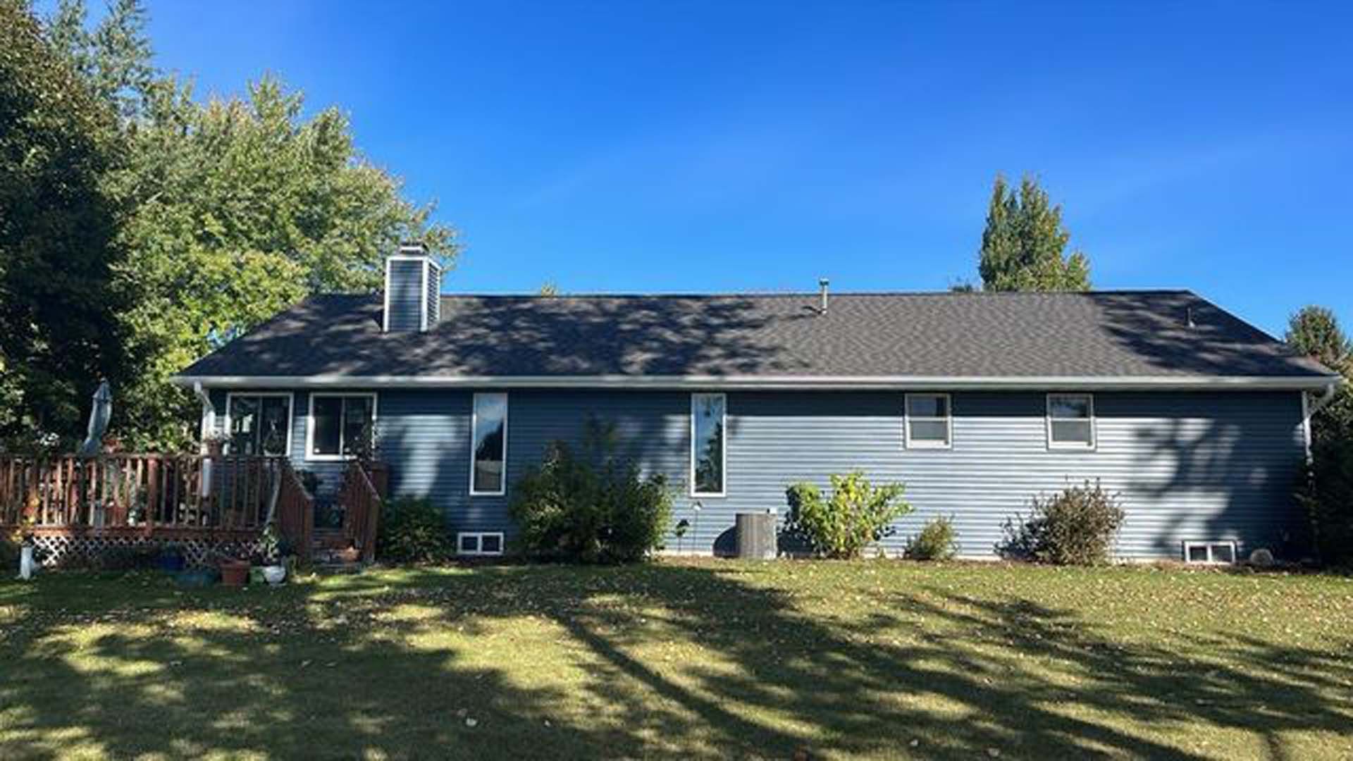 A large house with a gray roof is sitting on top of a lush green field.