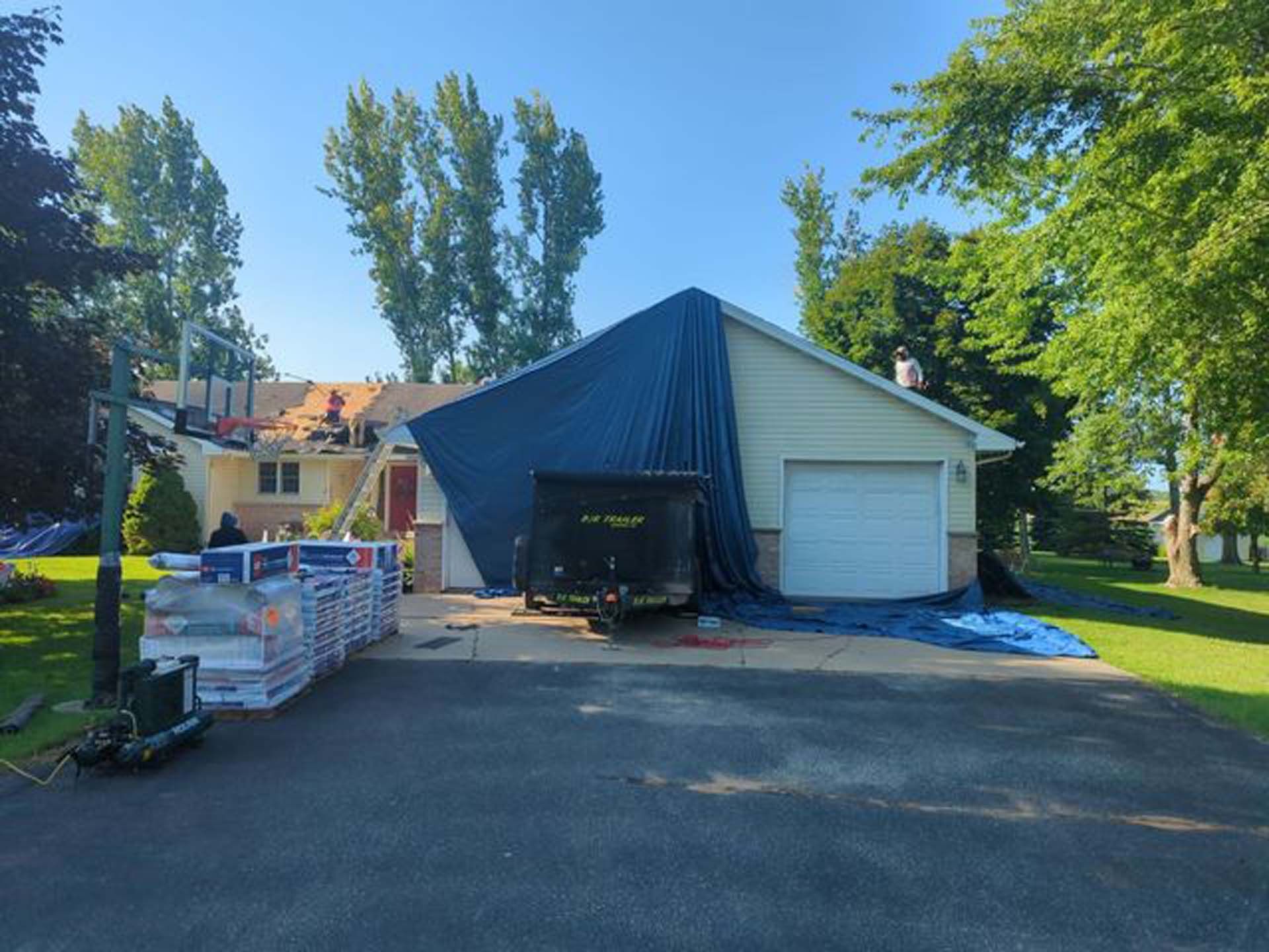 A house with a blue tarp on the roof is being remodeled.