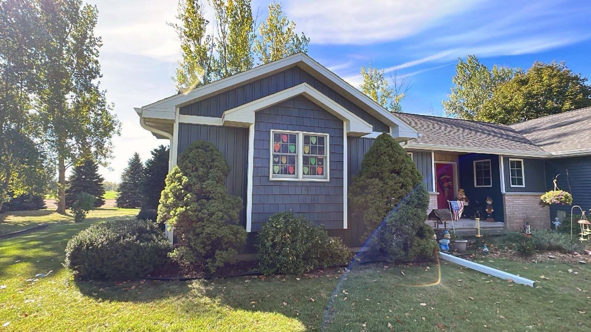A small house with a porch and trees in front of it.