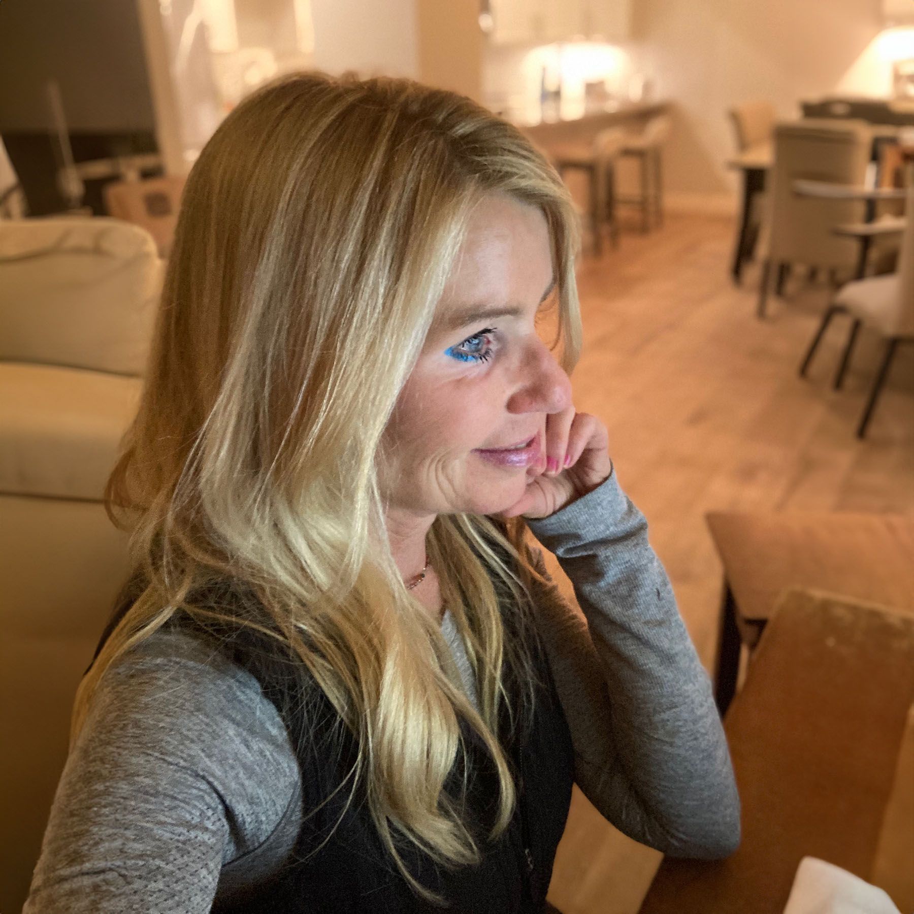 Diane Birnholz sitting at a table with her hand on her chin, writing her latest novel.