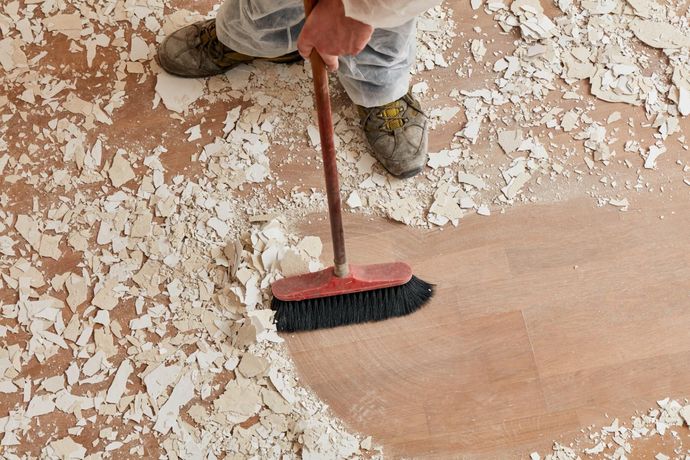 A person is cleaning the floor with a broom.