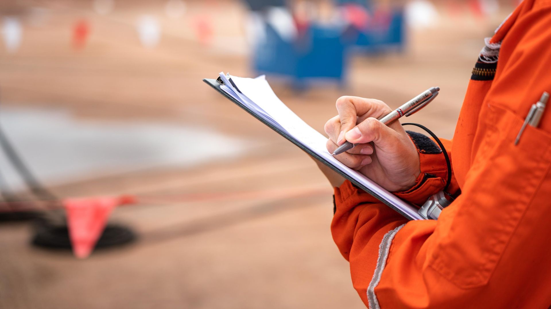 A person is writing on a clipboard with a pen.