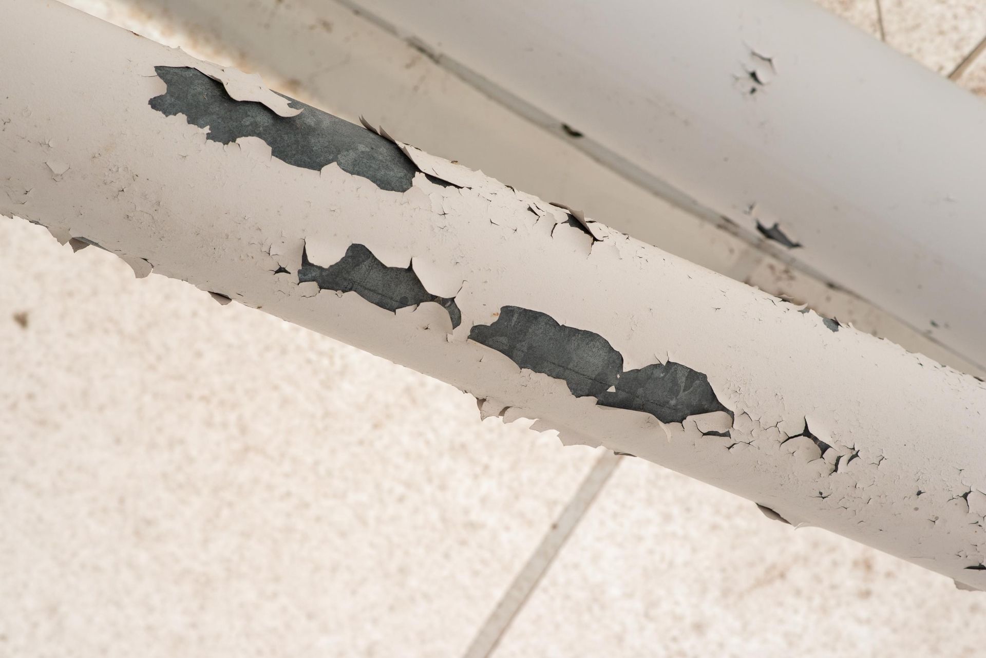 A close up of a white pipe with peeling paint.