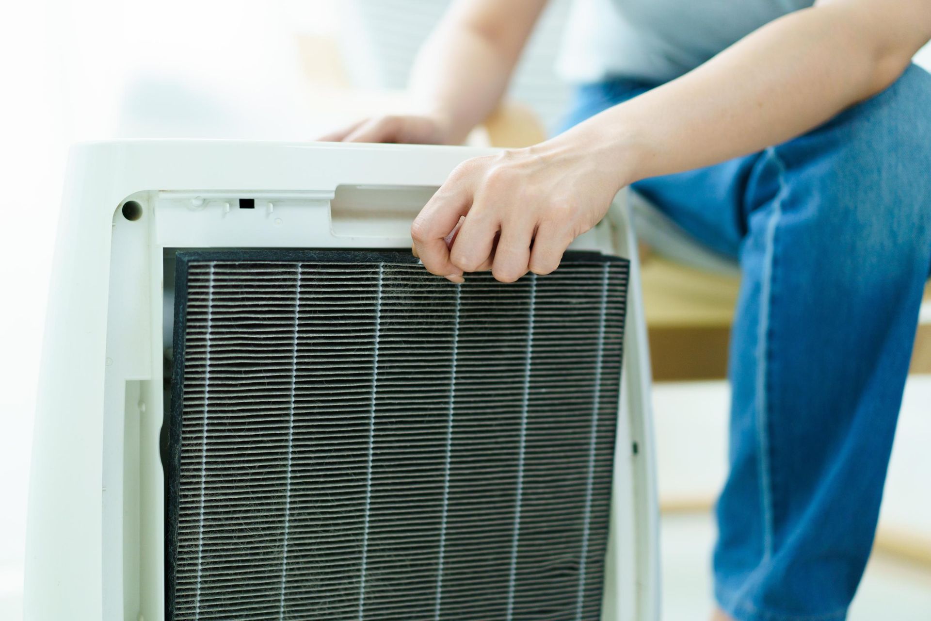 A person is cleaning a filter on an air purifier.