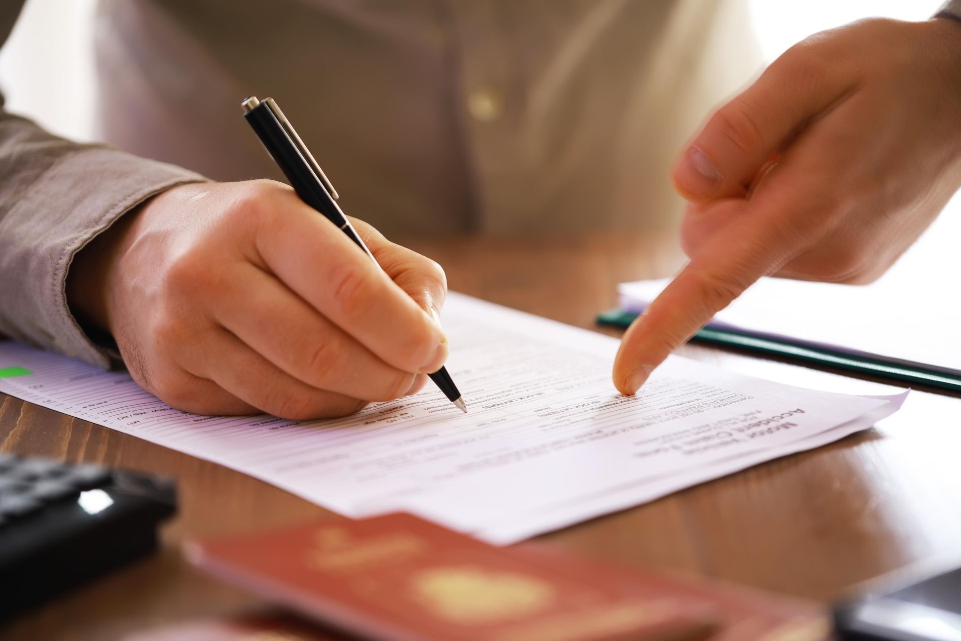 A person is writing on a piece of paper and pointing at it.