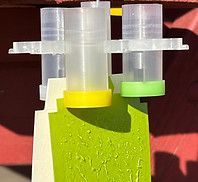 A close up of a plastic container with a yellow cap on a green and white object.