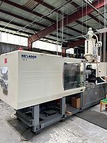 A large plastic injection molding machine is sitting inside of a building.