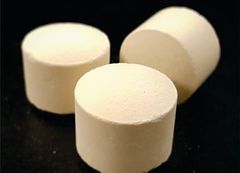 Three white cylinders are sitting on top of each other on a black surface.