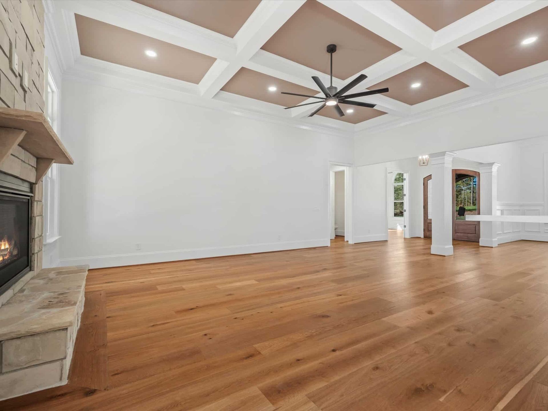 An empty living room with hardwood floors and a fireplace.