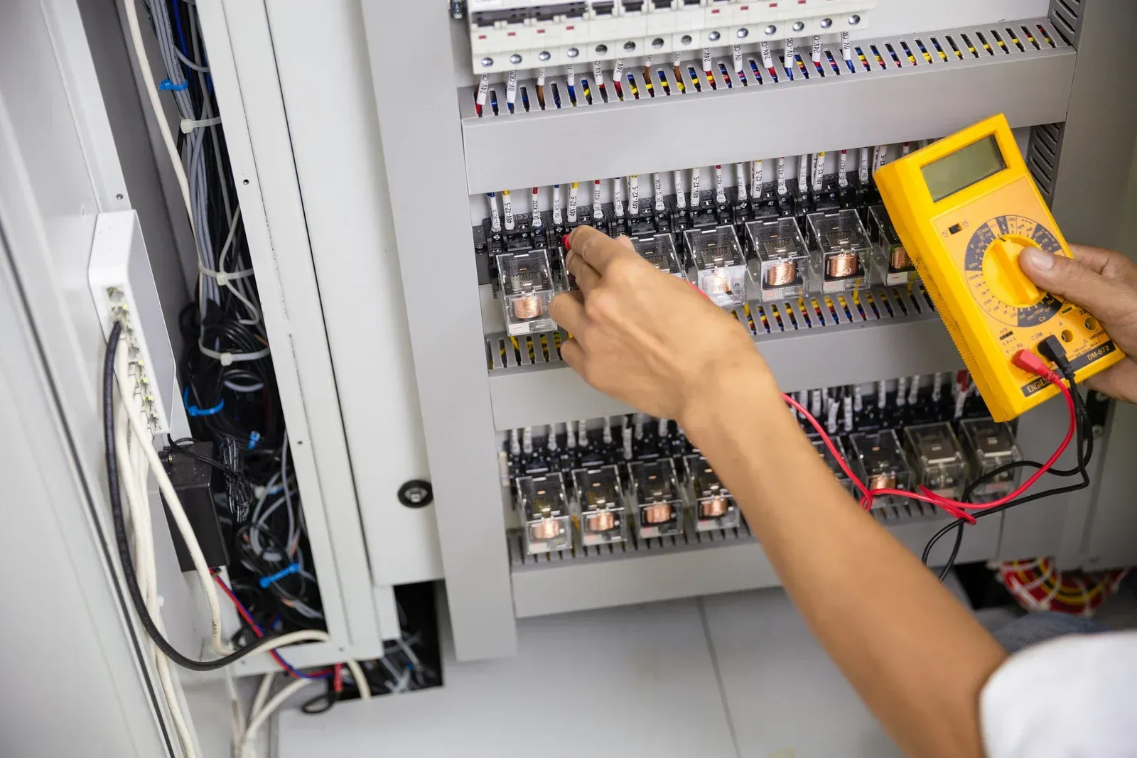 A person is using a digital multimeter to test a circuit board.