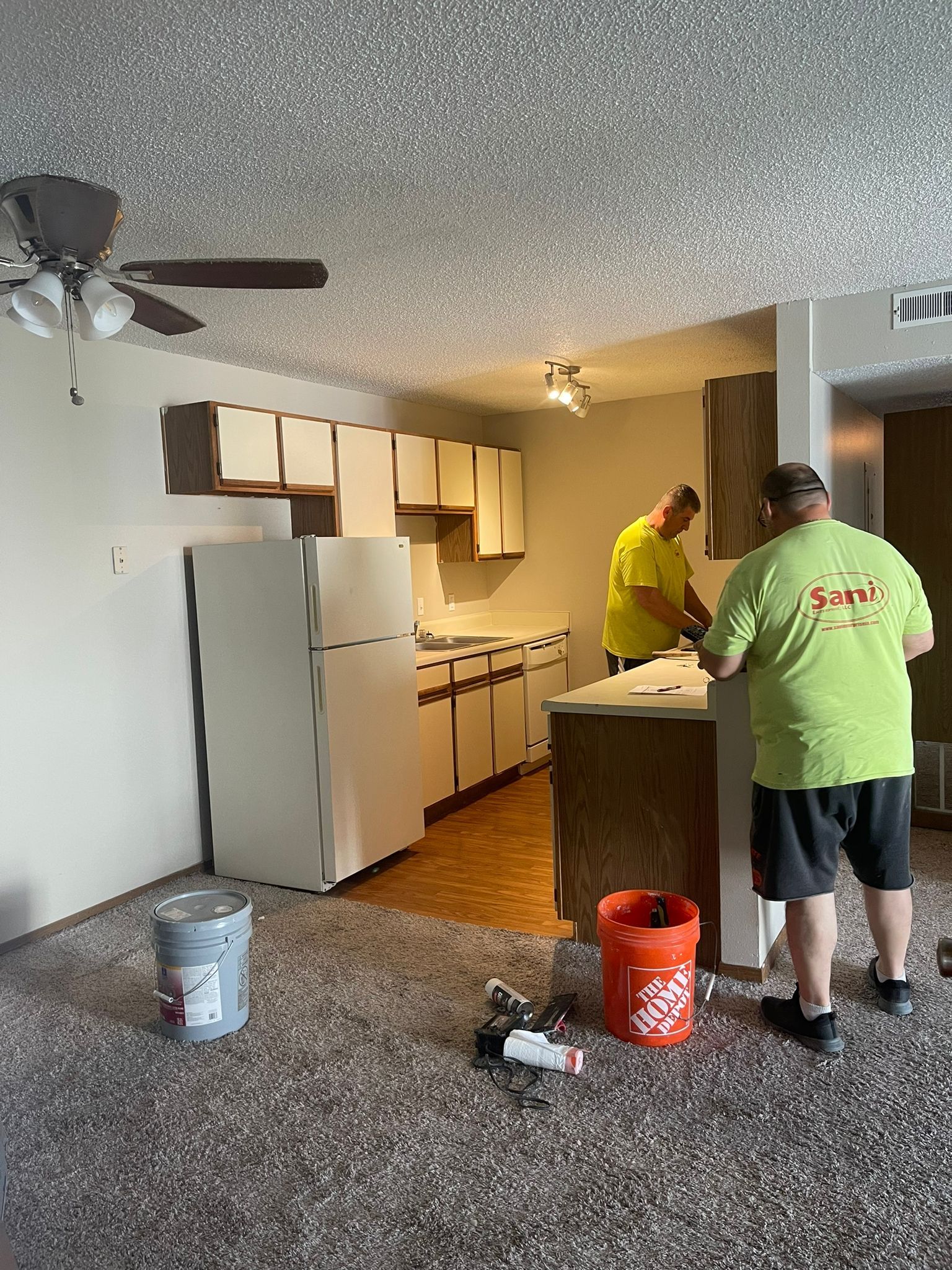 Two men are painting a kitchen in a house.