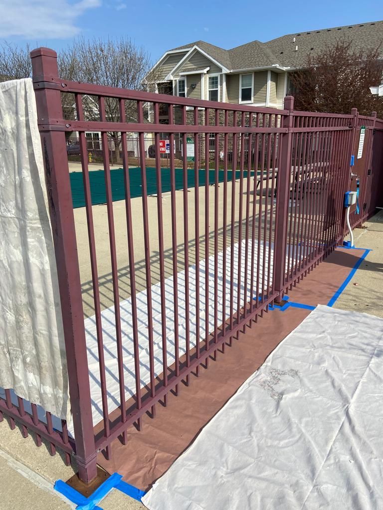A fence is being painted in front of a house.