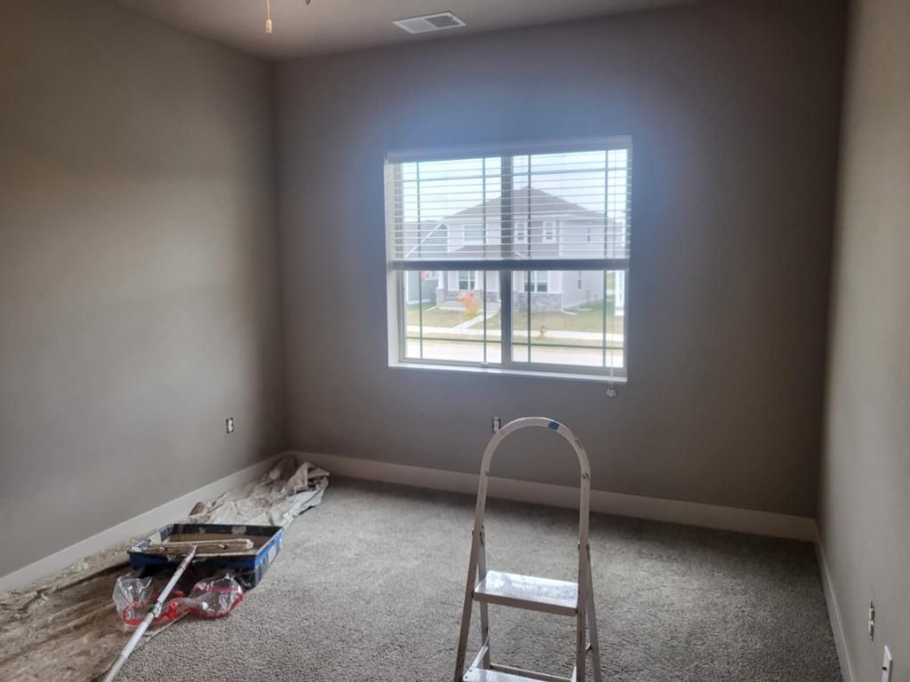 An empty room with a window and a ladder in it.