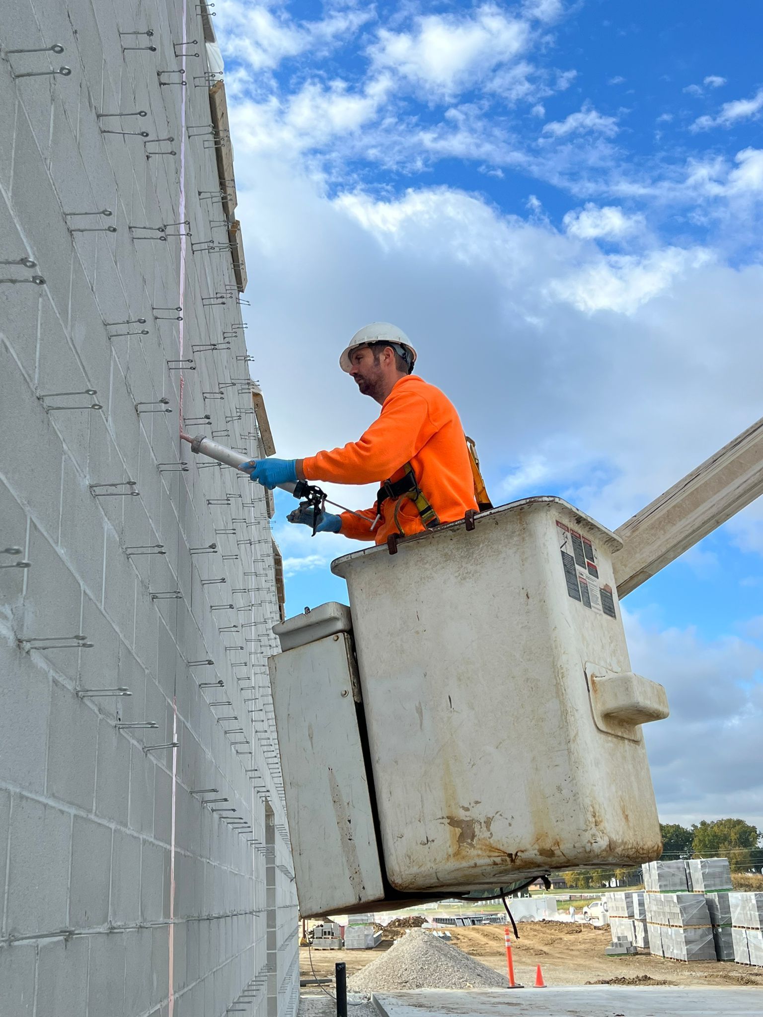 A man is sitting in a bucket on top of a crane.