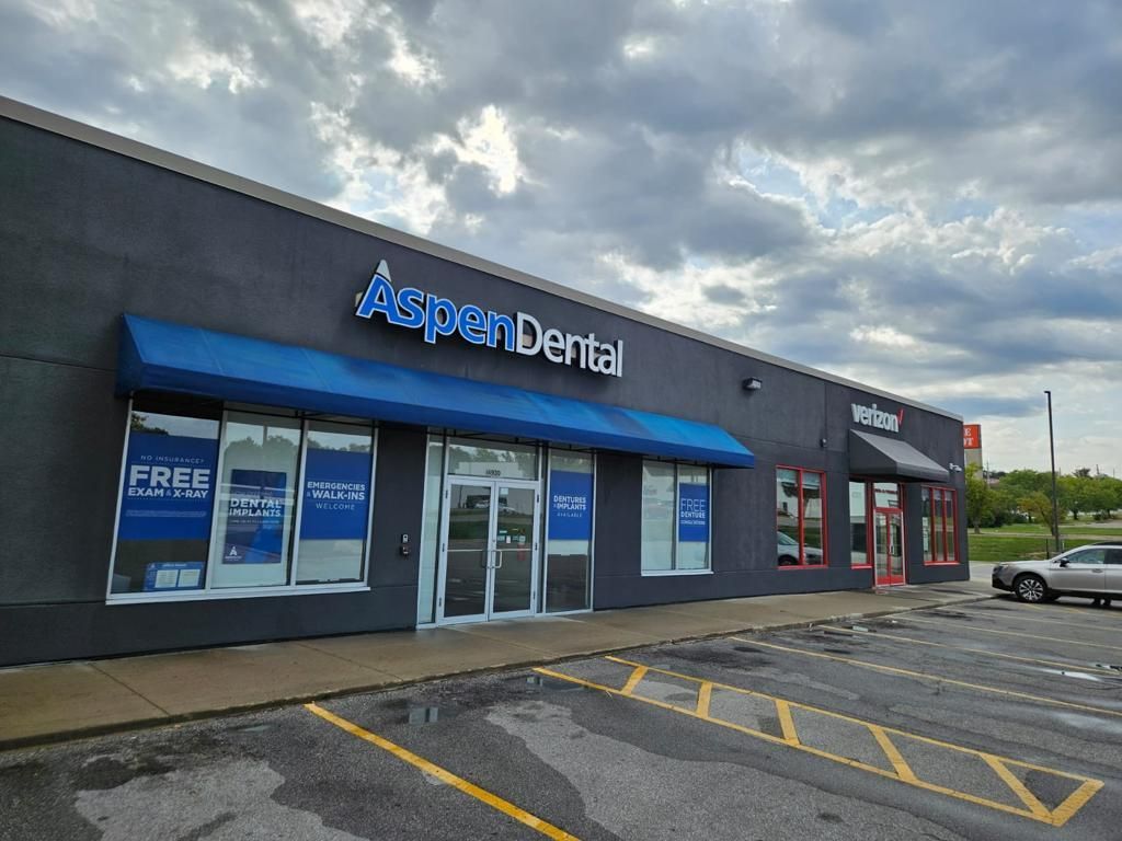 A dental office with a blue awning and a white truck parked in front of it.