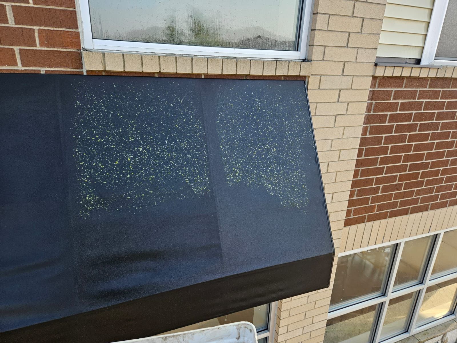 A black awning is on the side of a brick building.