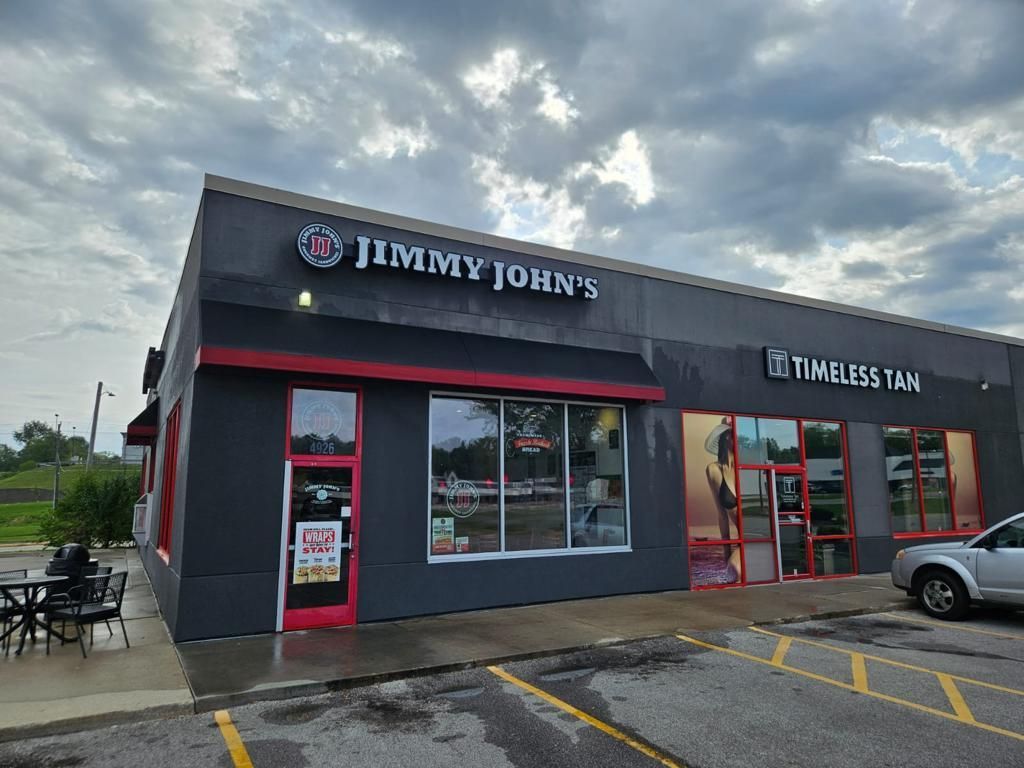 A jimmy john 's restaurant with a car parked in front of it.