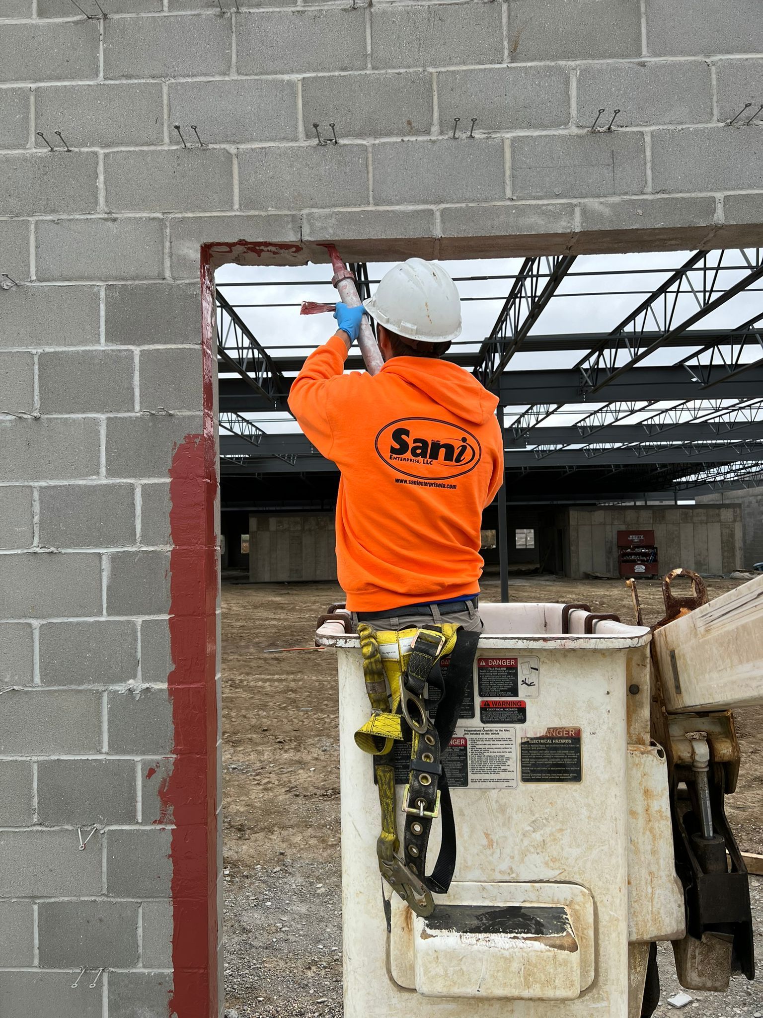 A construction worker is working on a brick wall in a bucket.