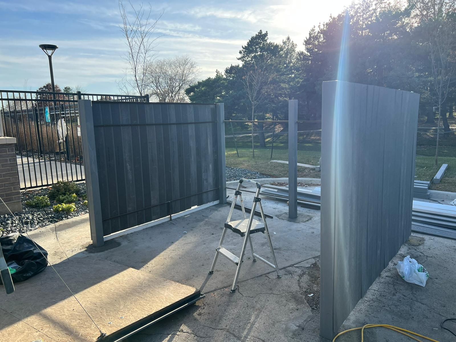 A ladder is sitting on the ground next to a wooden fence.