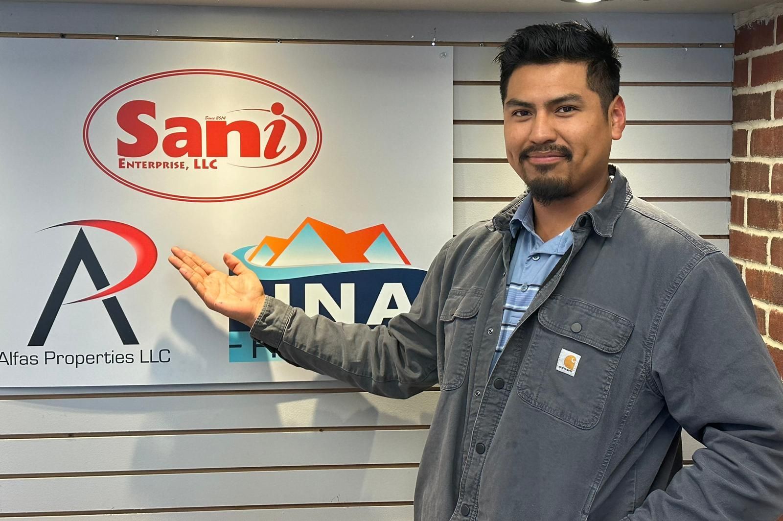 A man is standing in front of a sign that says sani