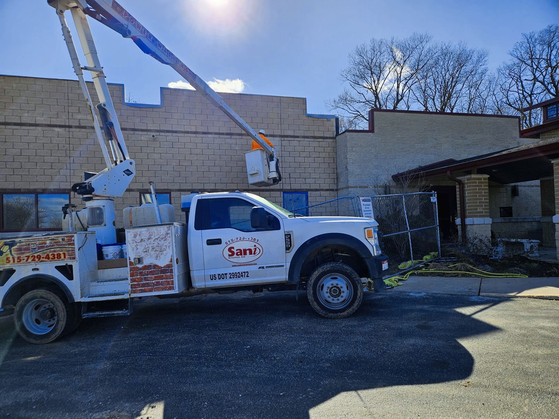 A white truck with a crane on top of it is parked in front of a building.