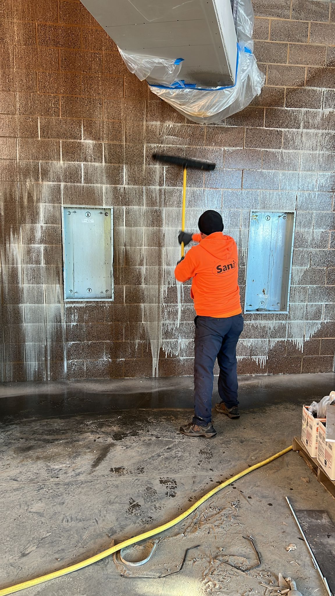 A man is cleaning a brick wall with a broom.