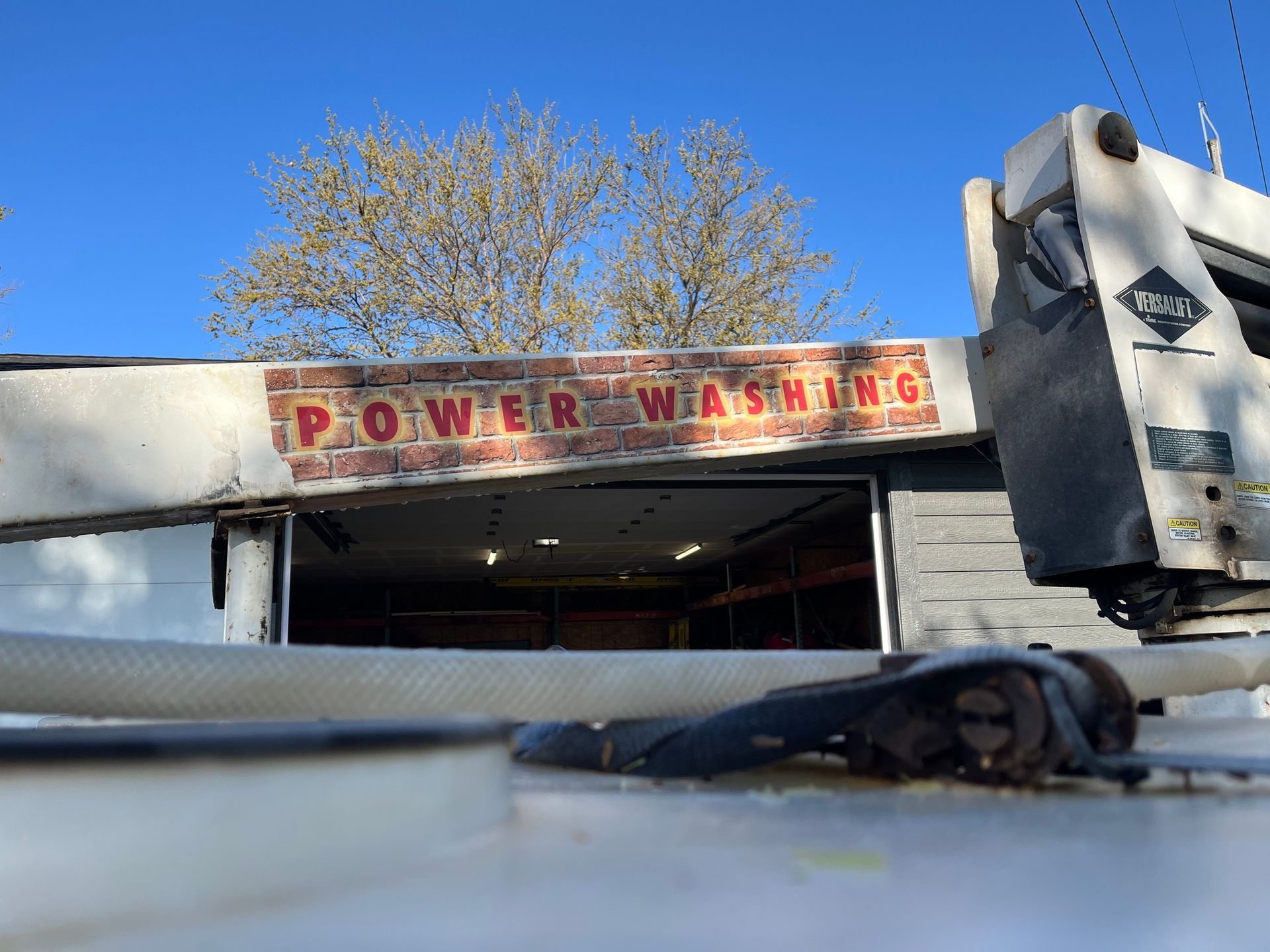 A power washing truck is parked in front of a brick building.
