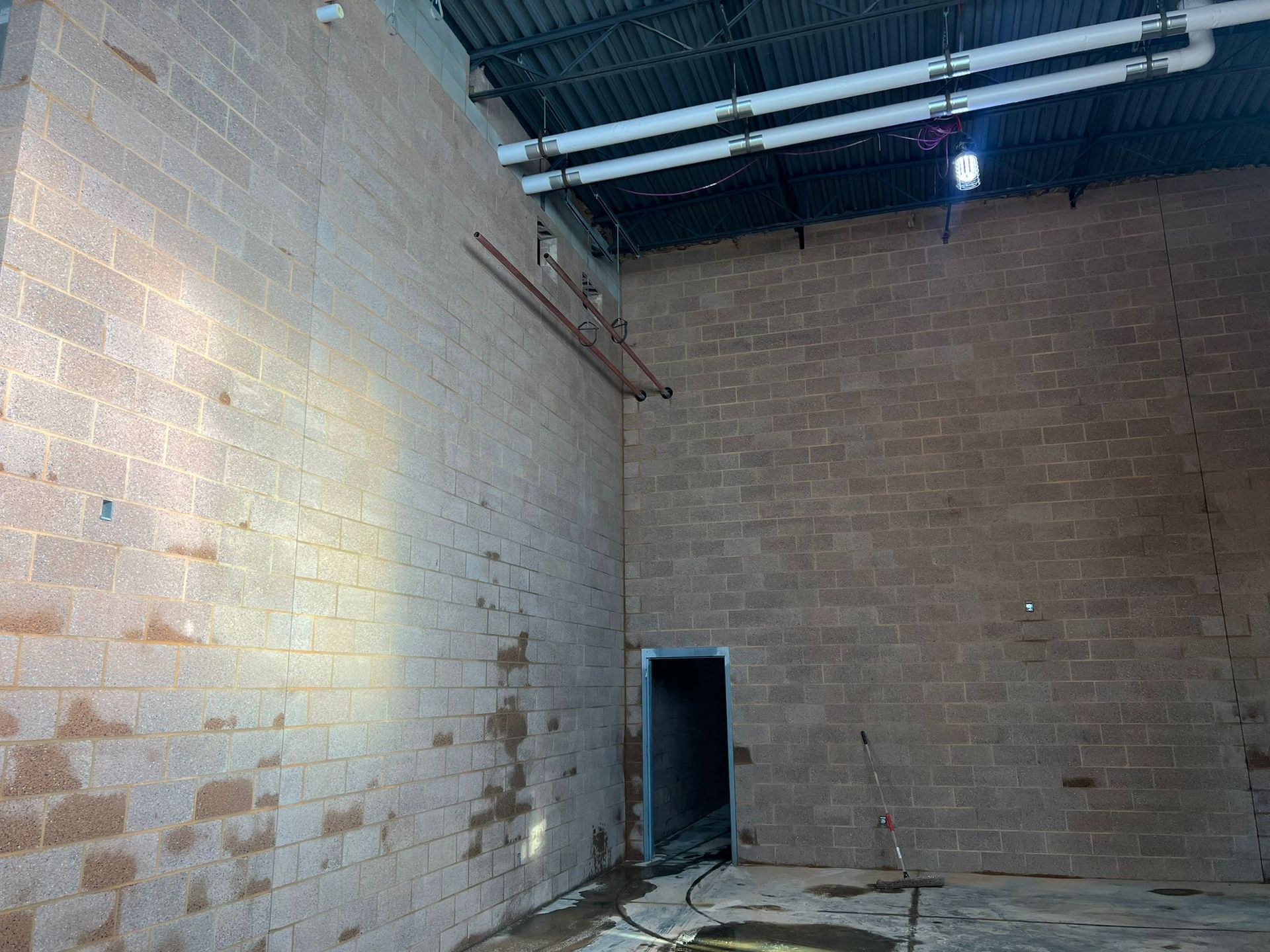 An empty room with a brick wall and a door.