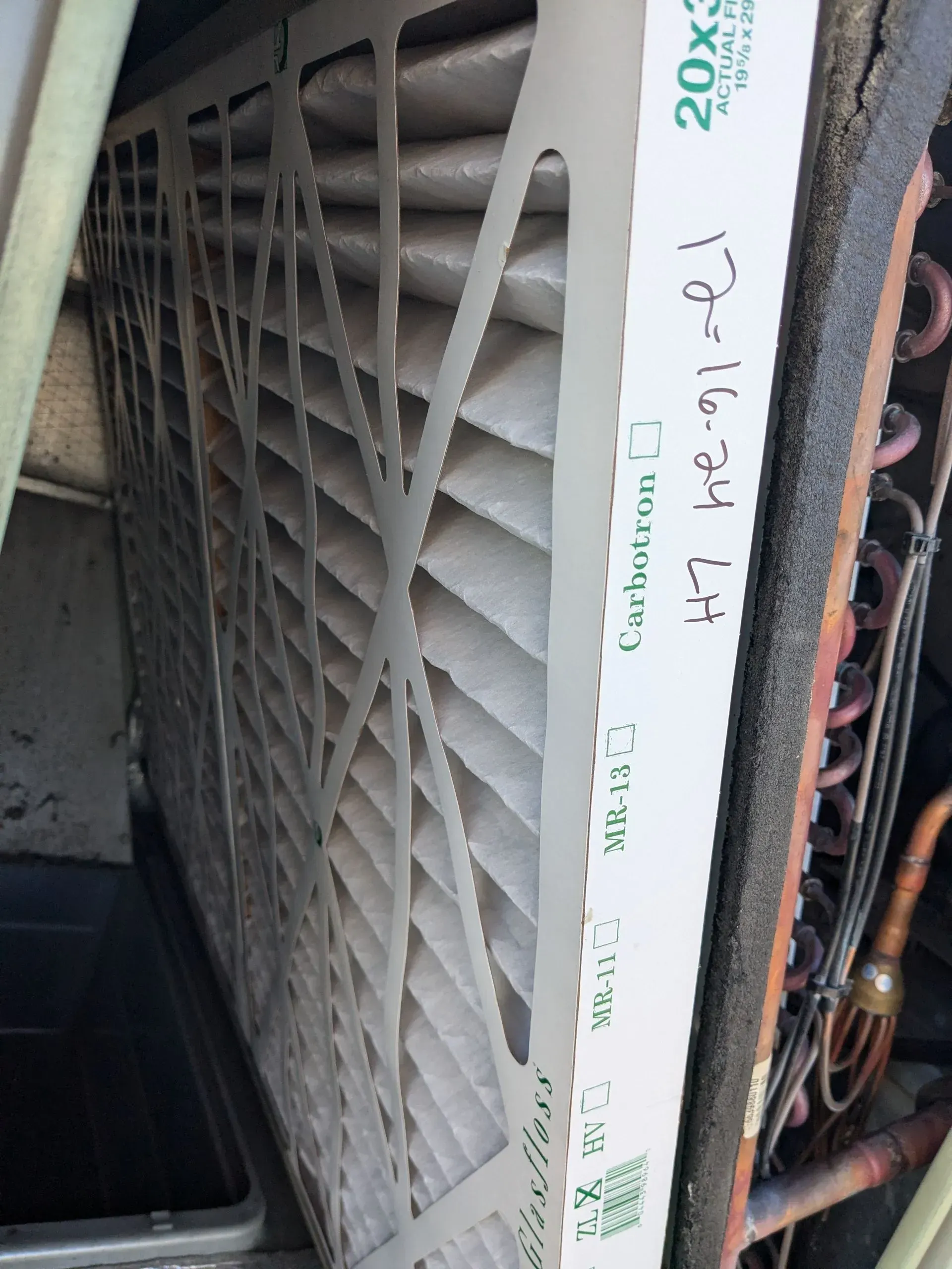 A dirty HVAC filter, 20x30x1 size, inside an air handler.