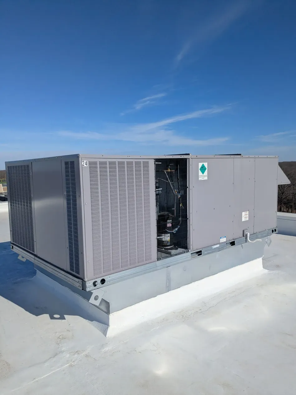 Gray air conditioning unit mounted on a brick wall, with power cable and conduit.
