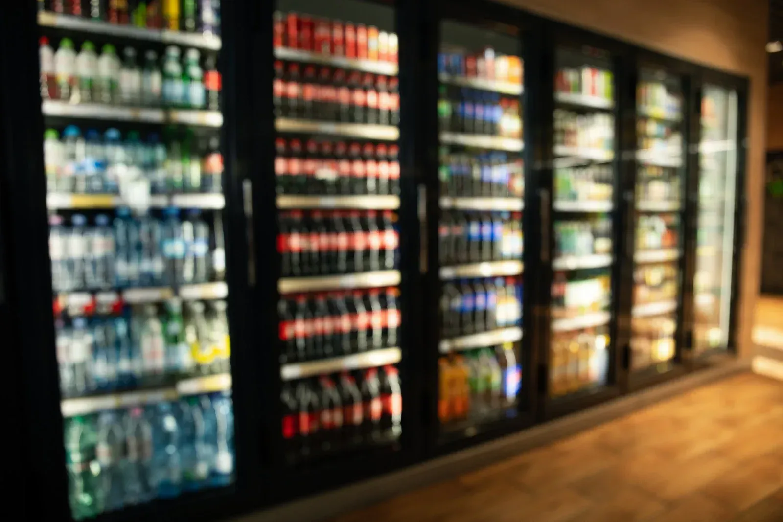 Refrigerated glass doors filled with colorful beverages in a convenience store.