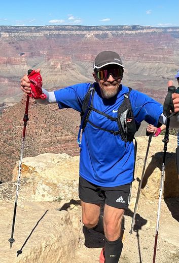 A man is standing on top of a mountain holding hiking poles.