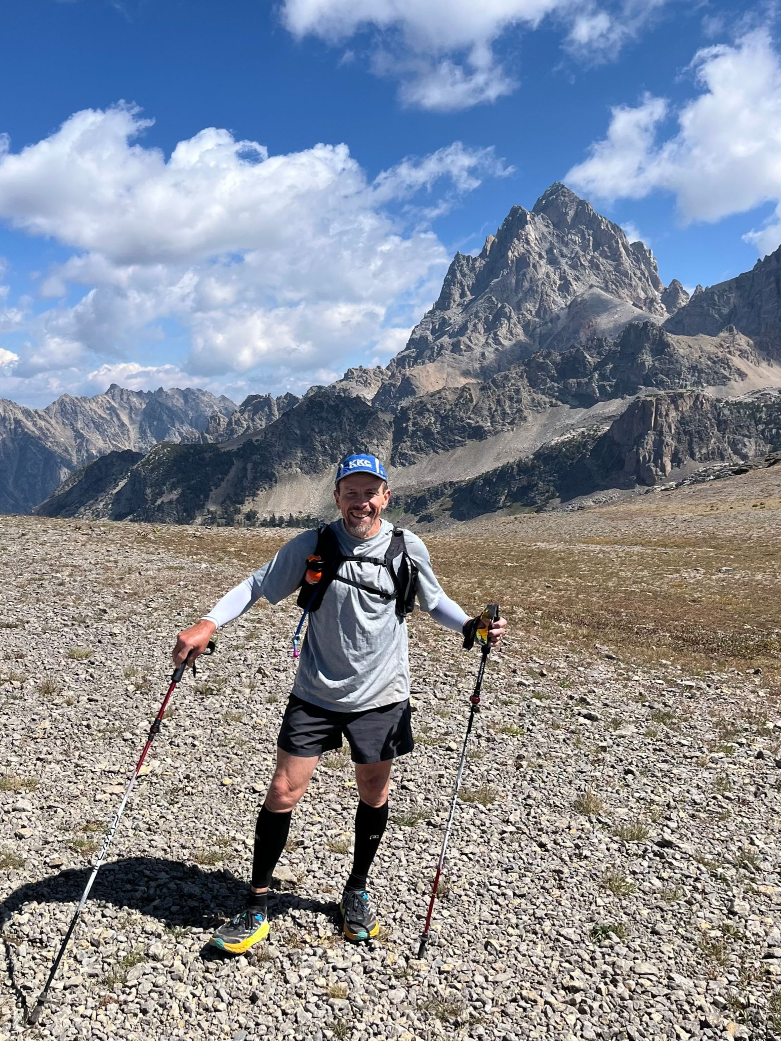 A man in a blue shirt and black shorts is walking on a trail.