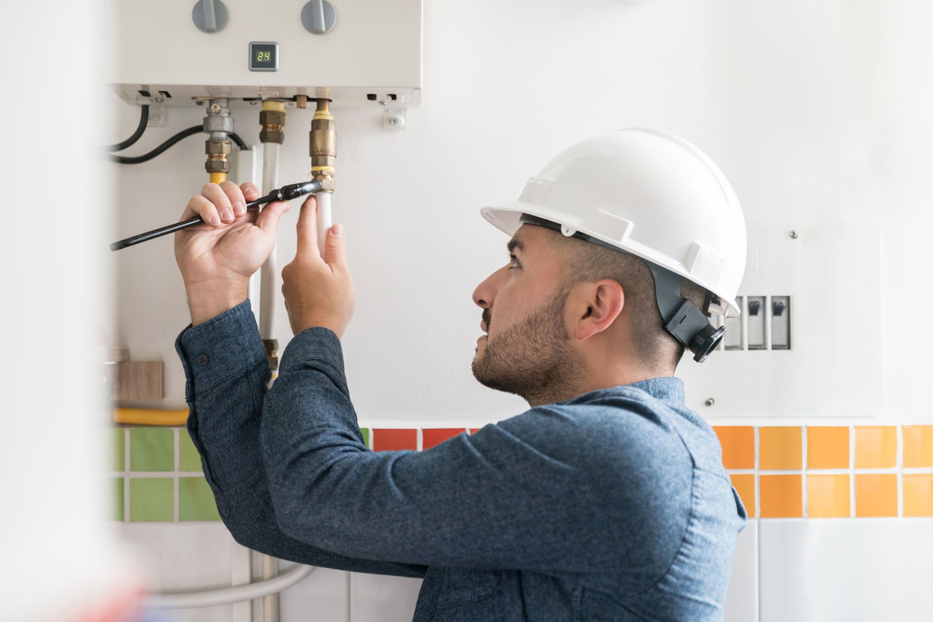 Technician using a wrench, for water heater installation in Huntington, MD.