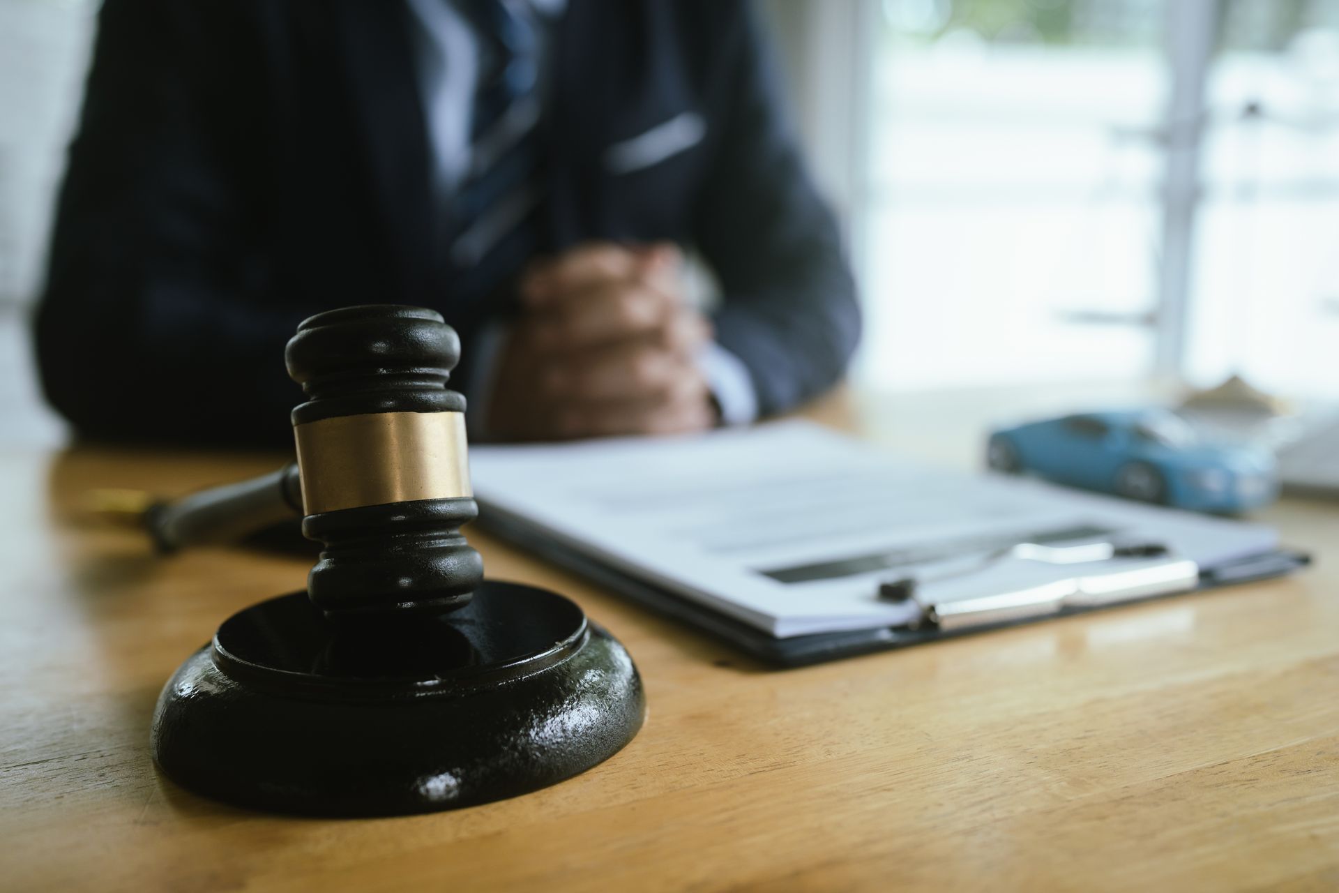 Professional car accident injury lawyer at desk with gavel, legal documents, and a model car.