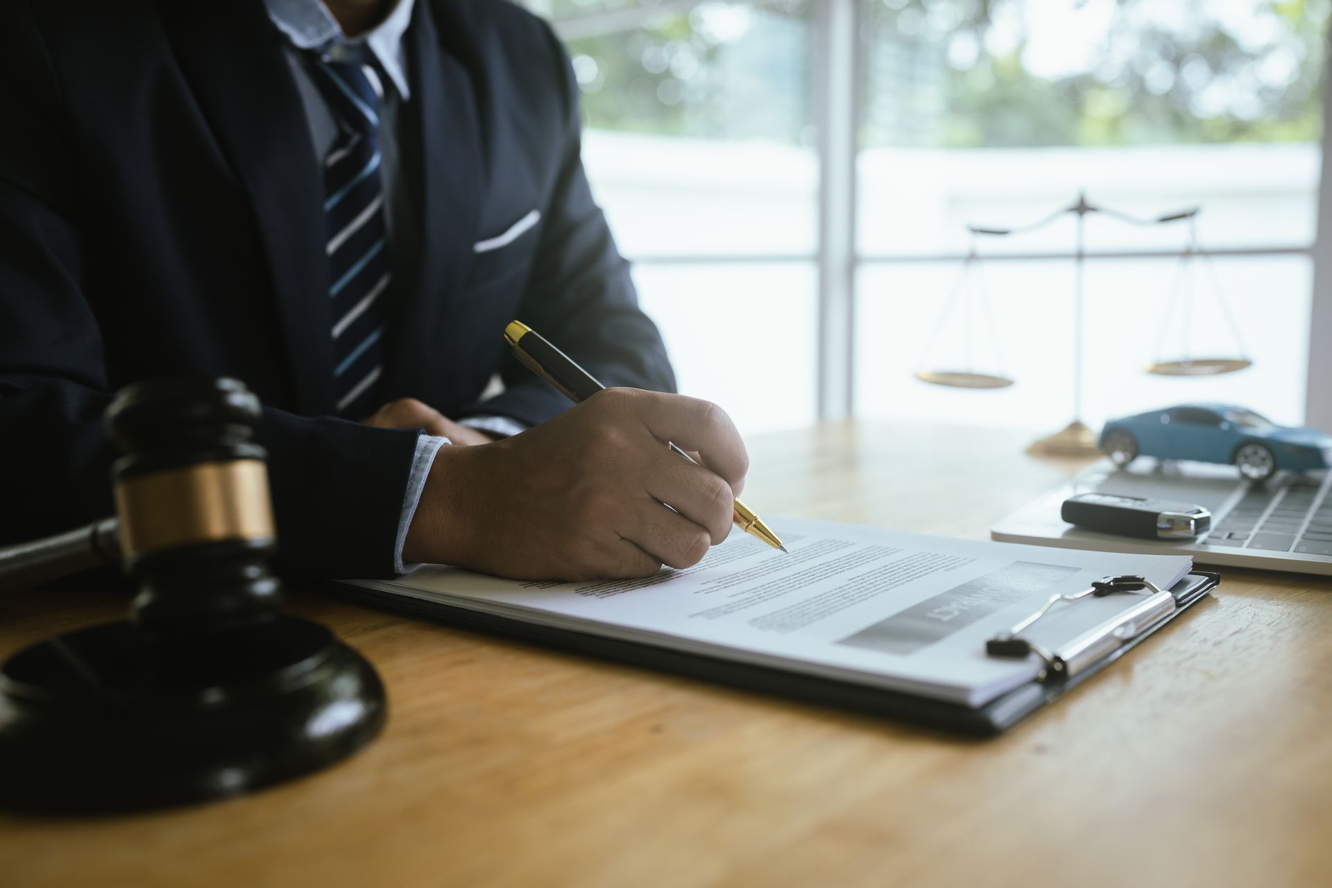 An auto injury attorney in a suit signs legal documents with a pen.