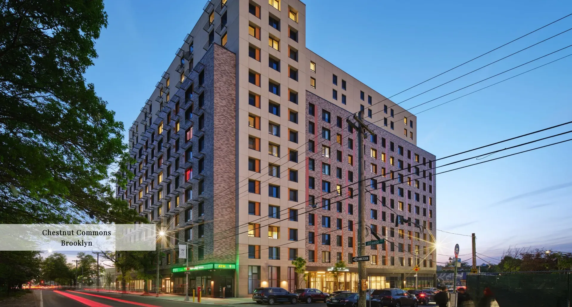 Bathroom with gray tile, white tub, vanity, black fixtures, and a mirror.