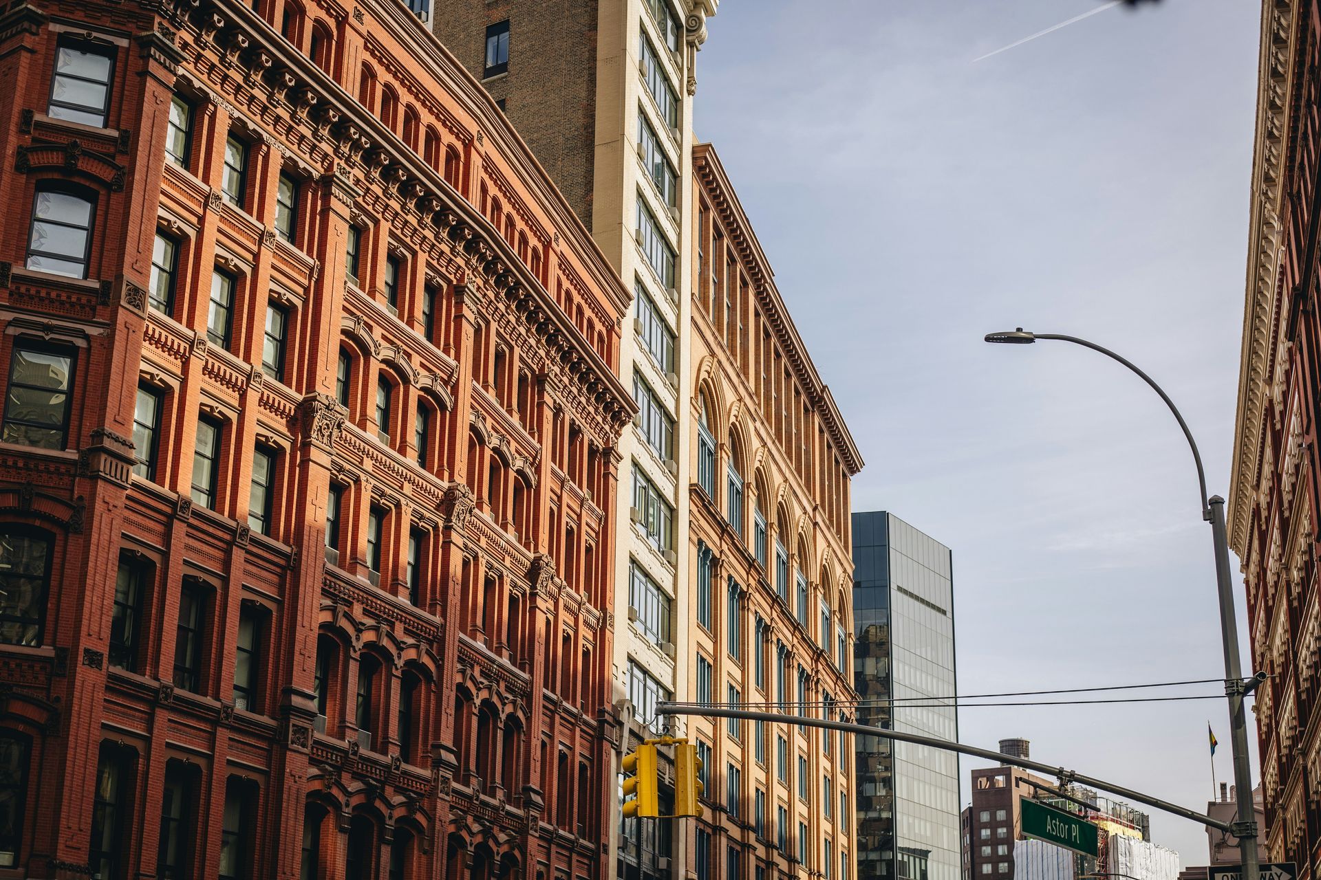 A perspective view of historic red brick and light-colored stone buildings under a clear sky in a city.