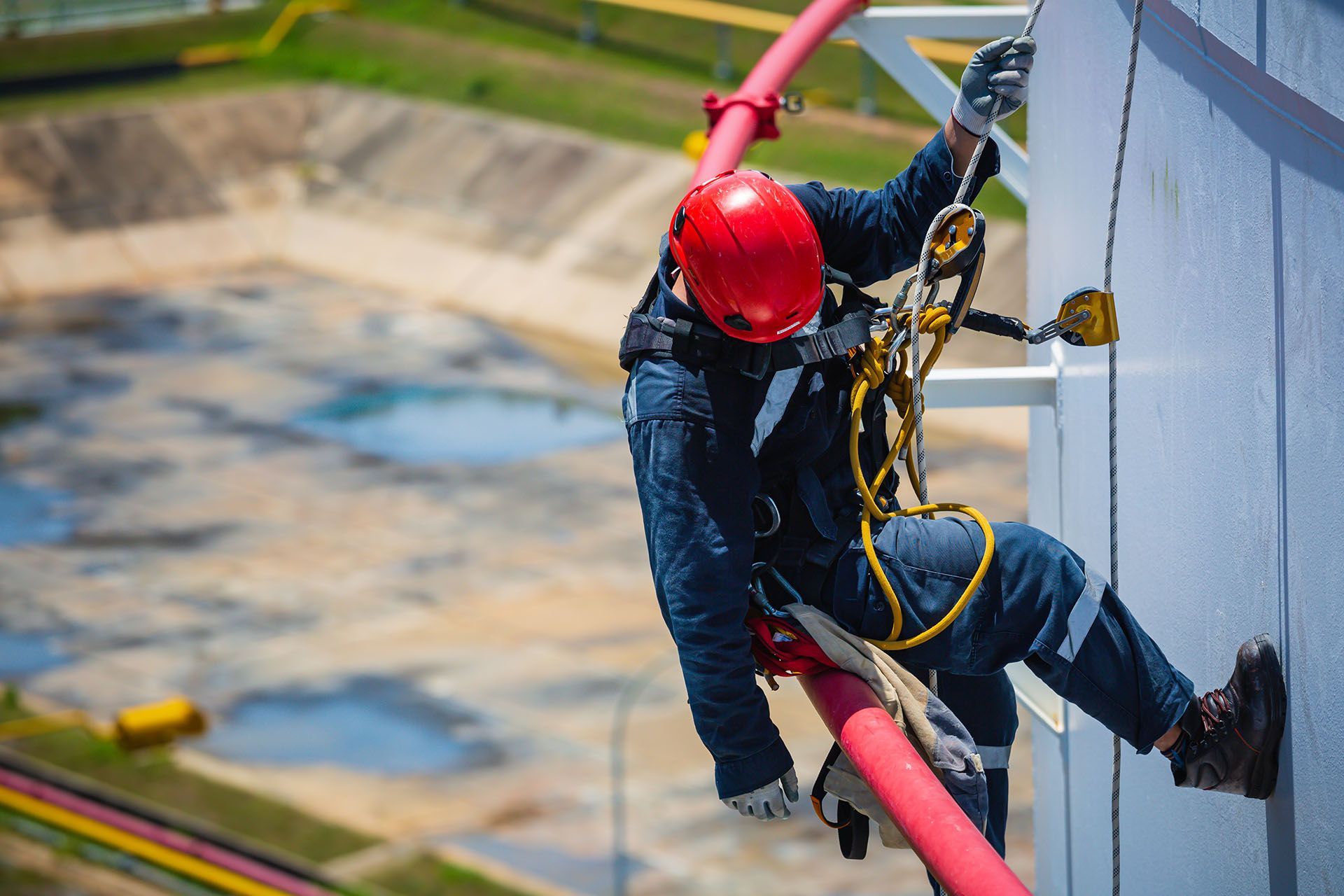 A man in a red helmet is climbing a building.