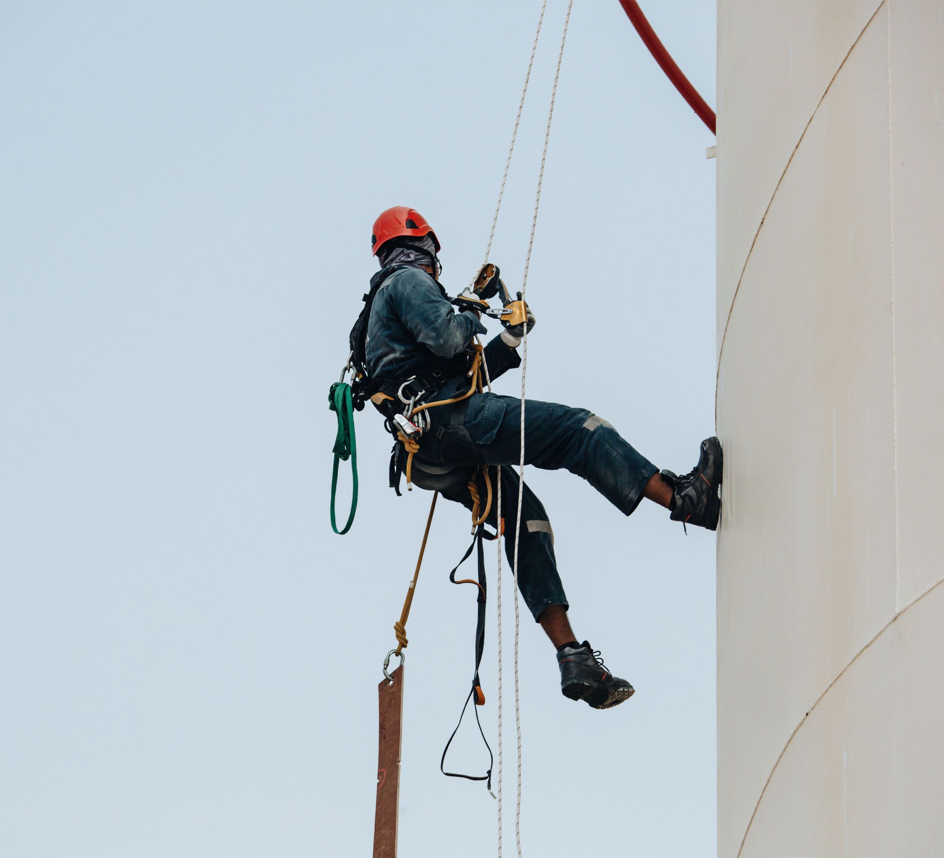 A man is hanging from a rope while climbing a building.