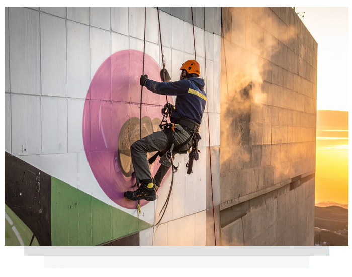Man remove a graffiti using rope access